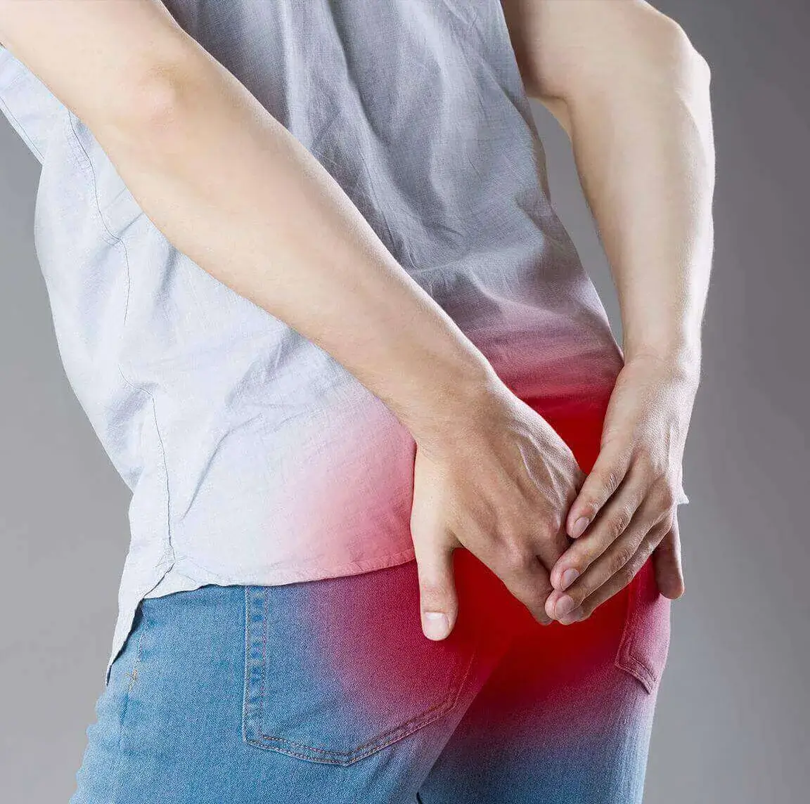 A man clutching his buttocks with both hands, illustrating rectal pain or discomfort.