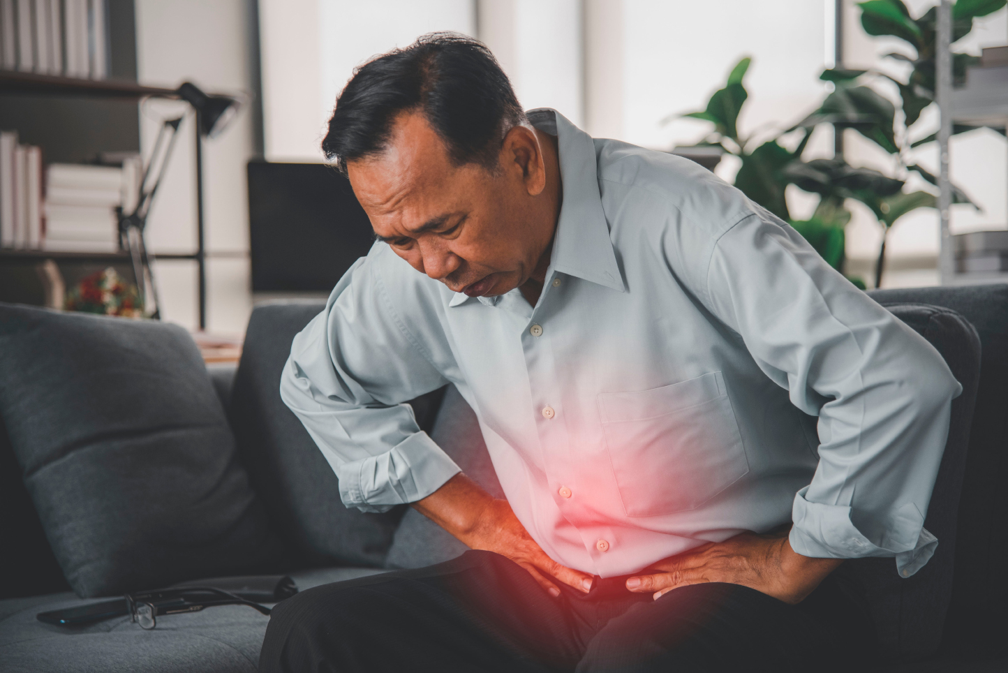 Man holding his lower abdomen in pain, illustrating persistent abdominal symptoms that may require colorectal assessment
