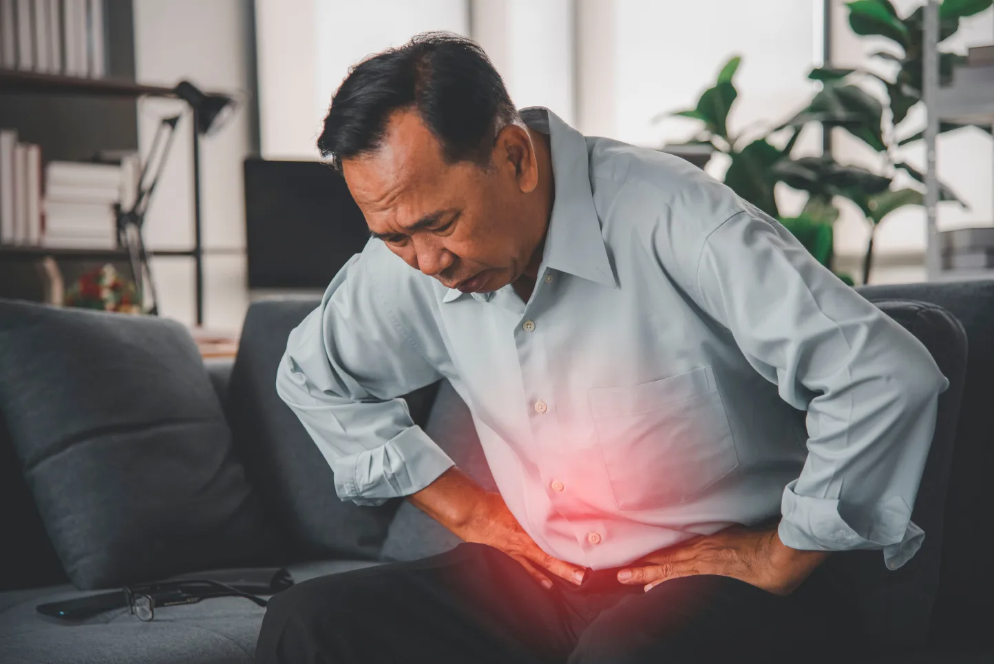 Man holding his lower abdomen in pain, illustrating persistent abdominal symptoms that may require colorectal assessment