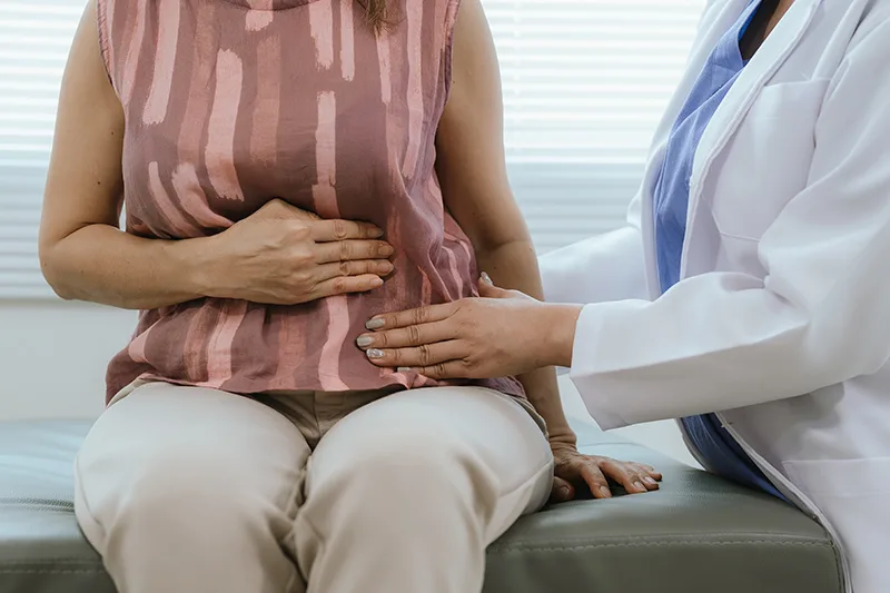 A patient experiencing abdominal pain during a colorectal consultation