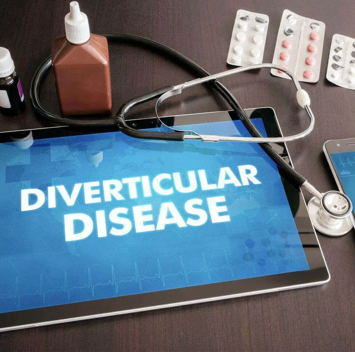 A stethoscope and medication next to a tablet screen reading 'Diverticular Disease