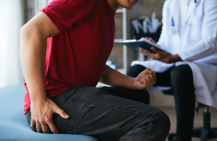 A man sitting while holding his hip from joint pain